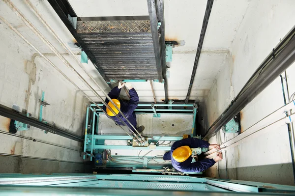 Maquinistas ajustando elevador no elevador de elevação — Fotografia de Stock