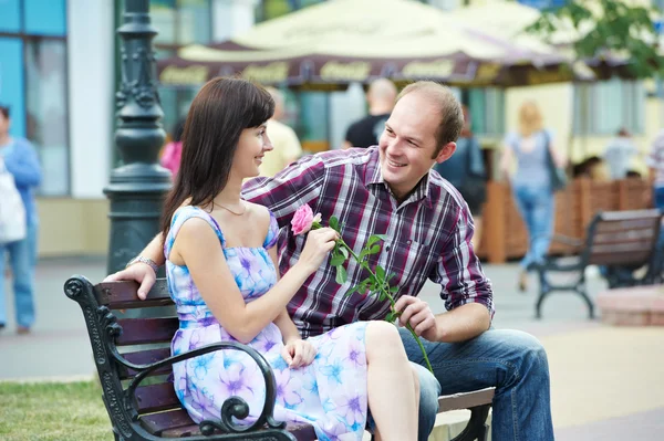 Człowiek i dziewczyna z kwiatów na ulicy ławce na randkę — Zdjęcie stockowe