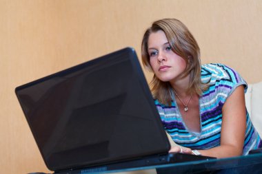 Young woman playing in games on laptop. clipart