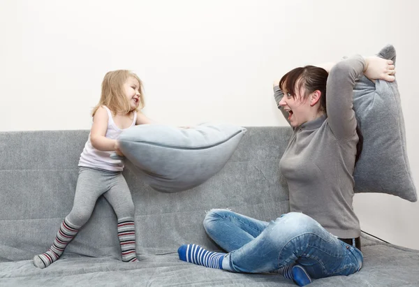 Criança e jovem mãe travesseiro lutando no sofá . — Fotografia de Stock