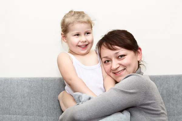 Mother and her little daughter sitting and couch — Stock Photo, Image
