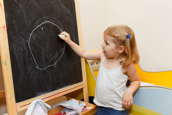 Meisje tekeningen met krijt op blackboard — Stockfoto