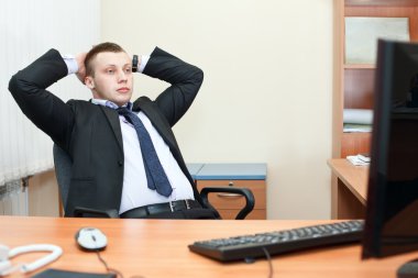 Portrait of relaxed business man sitting at his desk and thinking about som clipart