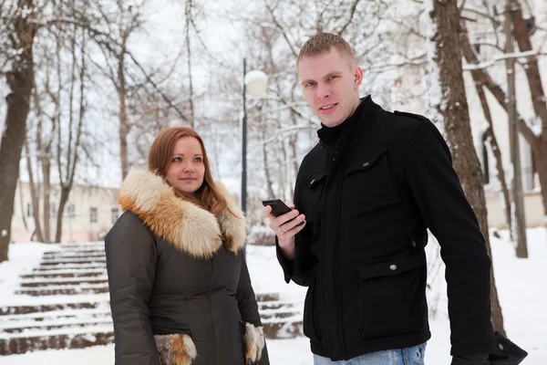Masculino com telefone e fêmea na temporada de inverno — Fotografia de Stock