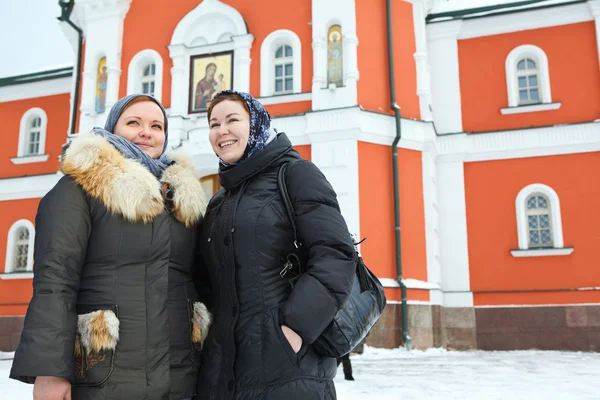 Два російських жінок в зимовий одяг проти православний монастир будівлі — стокове фото