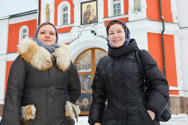 Due donne russe in abiti invernali contro l'edificio del monastero ortodosso — Foto Stock