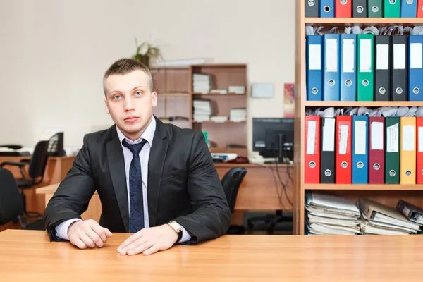 Handsome male business executive sitting behind a bookstand — Stock Photo, Image