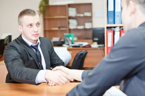 Young business man shaking hands with colleague across the table — Stock Photo, Image