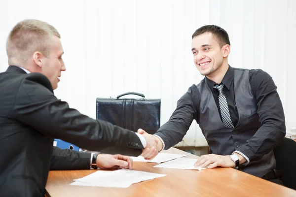 Jovem homem de negócios apertando as mãos com colega do outro lado da mesa — Fotografia de Stock