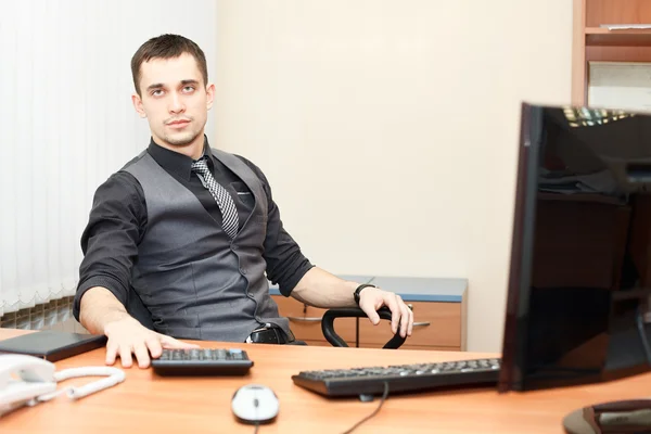 Joven hombre de negocios sentado en la mesa y trabajando en la computadora — Foto de Stock