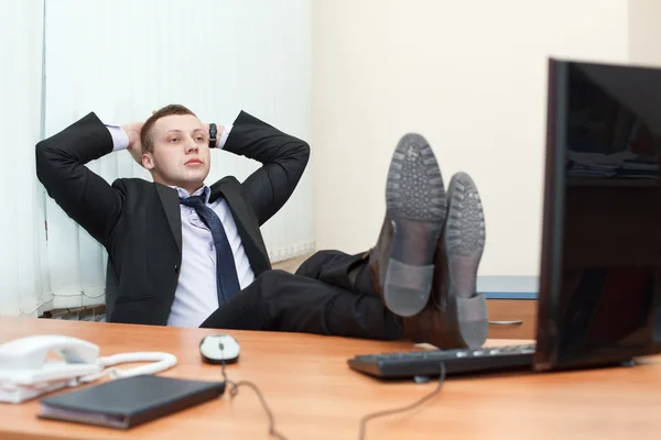 Beau jeune homme d'affaires reposant avec les pieds sur le bureau — Photo