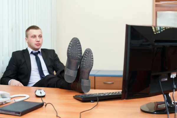 Csinos fiatal üzletember asztal lábakkal pihenő — Stock Fotó