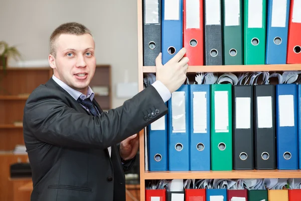 Handsome male business executive standing behind a bookstand — Stock Photo, Image