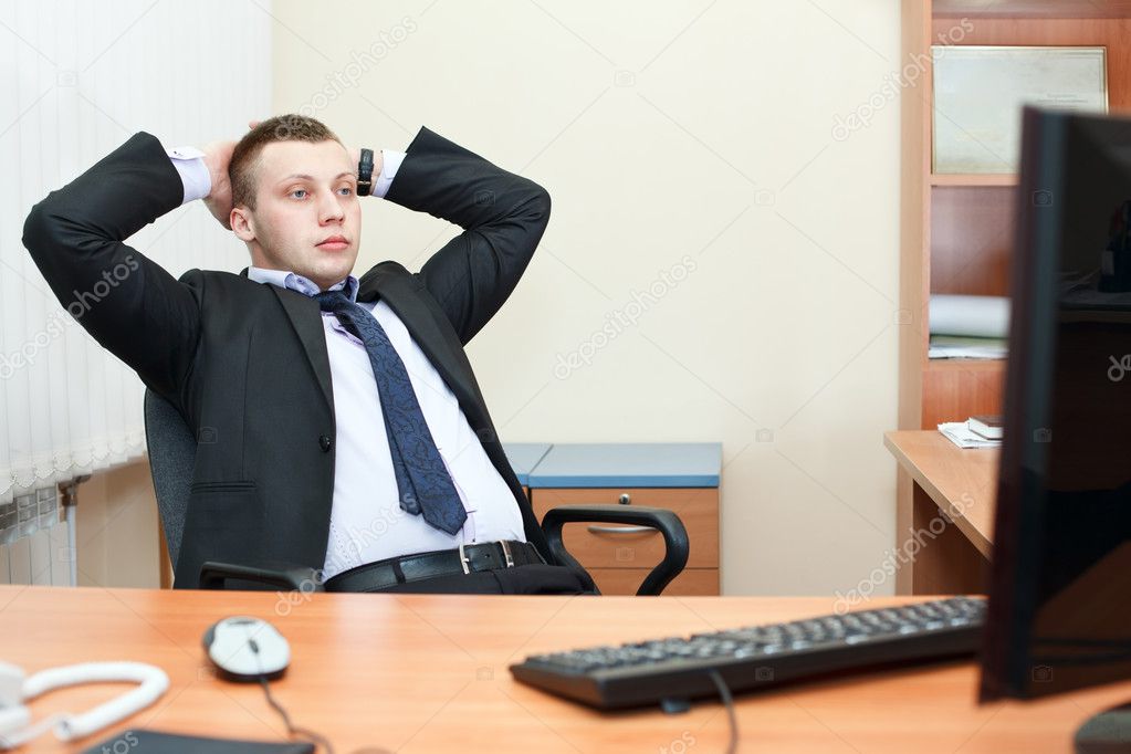 Portrait of relaxed business man sitting at his desk and thinking about som
