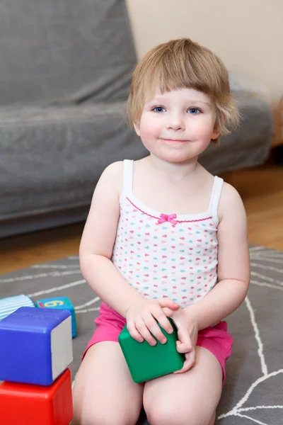 Porträt eines kleinen Mädchens, das mit Ziegeln auf dem Boden spielt — Stockfoto