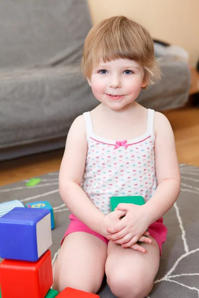 Retrato de niña jugando con ladrillos en el suelo —  Fotos de Stock