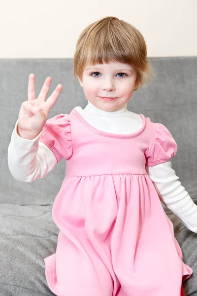 Retrato de menina pequena em vestido rosa mostrando três dedos na mão — Fotografia de Stock