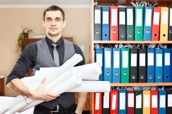 Handsome male business executive standing with rolled blueprints in hands — Stock Photo, Image