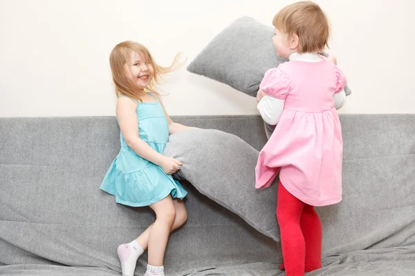 Two Caucasian happy playful little girls in pillows fighting — Stock Photo, Image