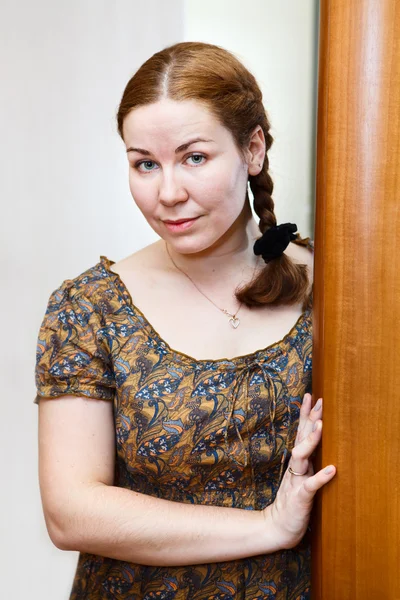 Portret van de jonge Kaukasische vrouw in jurk staande op binnenlandse kamer — Stockfoto