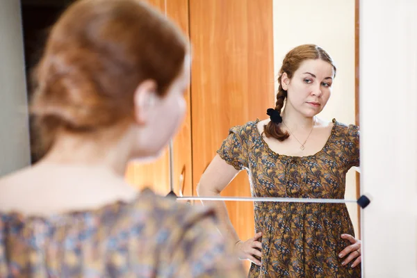 Портрет молодих кавказьких жінка в сукні стоячи проти дзеркало — стокове фото