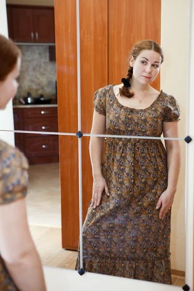 Retrato de jovem caucasiana fêmea de vestido em pé contra espelho — Fotografia de Stock