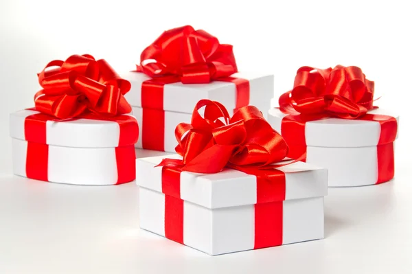 Four white gift boxes with red satin ribbon — Stock Photo, Image