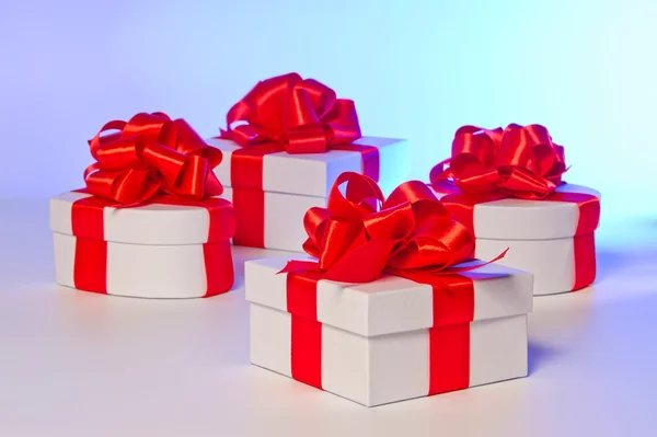 Vier weiße Geschenkboxen mit rotem Satinband — Stockfoto