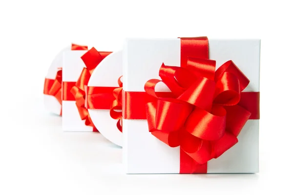 Four white gift boxes with red satin ribbon — Stock Photo, Image