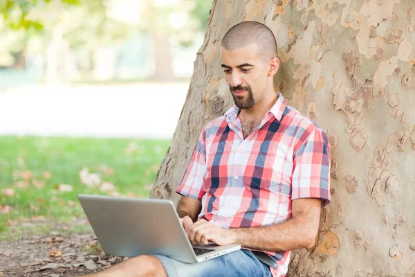 Hombre joven con computadora en el parque —  Fotos de Stock