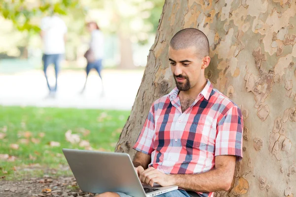 Νεαρός άνδρας με υπολογιστή στο πάρκο — Φωτογραφία Αρχείου