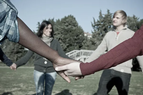 Multirassische junge Händchen haltend im Kreis — Stockfoto