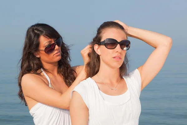 Ung kvinna klä sin vän hårstrån på Seaside — Stockfoto