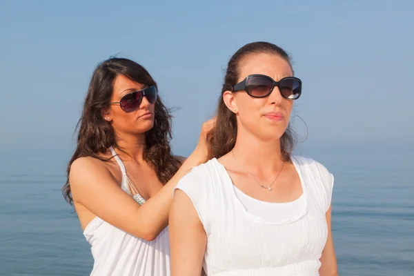 Mladá žena oblékat její přítel chloupky u moře — Stock fotografie