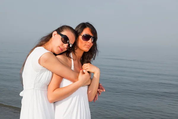 Twee vrouwelijke vrienden omarmd op het strand — Stockfoto
