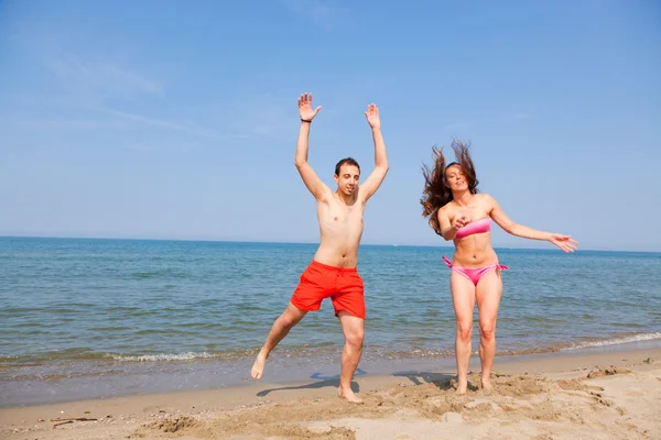 Szczęśliwa para skoki na plaży nad morzem — Zdjęcie stockowe