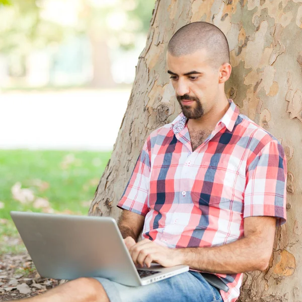 Hombre joven con computadora en el parque — Foto de Stock