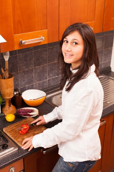 Mladá žena v kuchyni řezání zeleniny — Stock fotografie