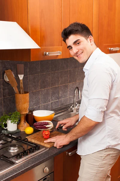 Человек режет помидор на кухне — стоковое фото