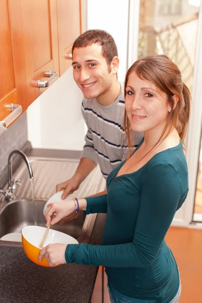 Esposa cozinhar enquanto marido lavar pratos — Fotografia de Stock