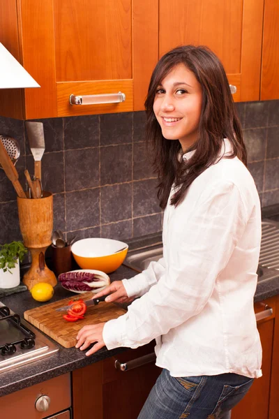 Молодая женщина режет помидоры на кухне — стоковое фото