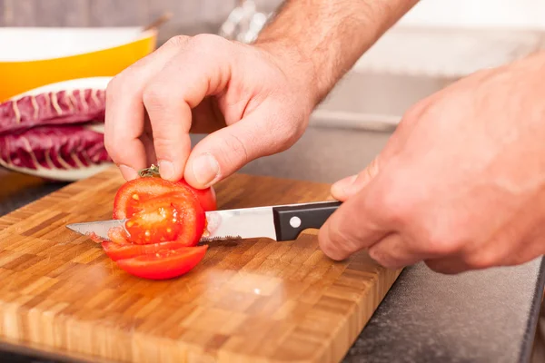 Man snijden tomaat in de keuken — Stockfoto