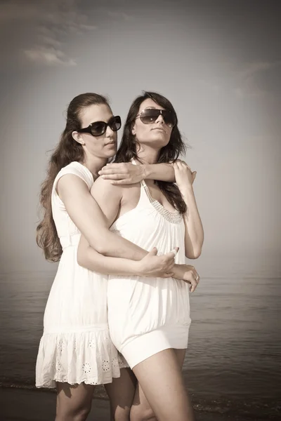 Två kvinnliga vänner omfamnade på stranden — Stockfoto