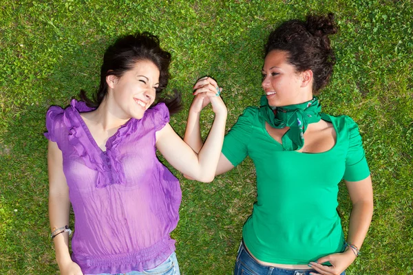 Dvě dívky, ležící na trávě a drželi se za ruce — Stock fotografie