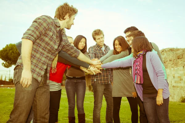 Estudantes multirraciais com as mãos na pilha — Fotografia de Stock