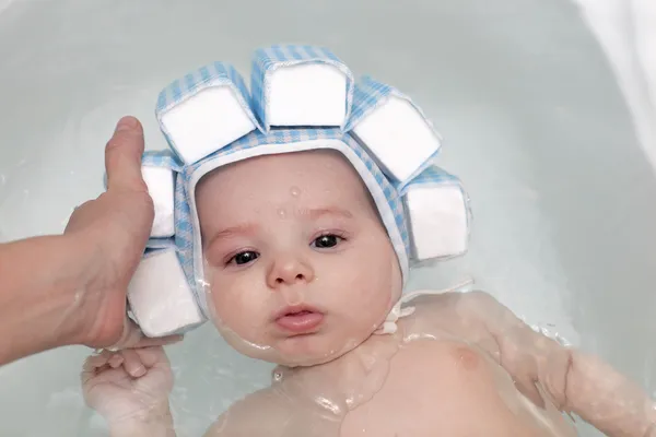 Baby in Badewanne in Badekappe — Stockfoto