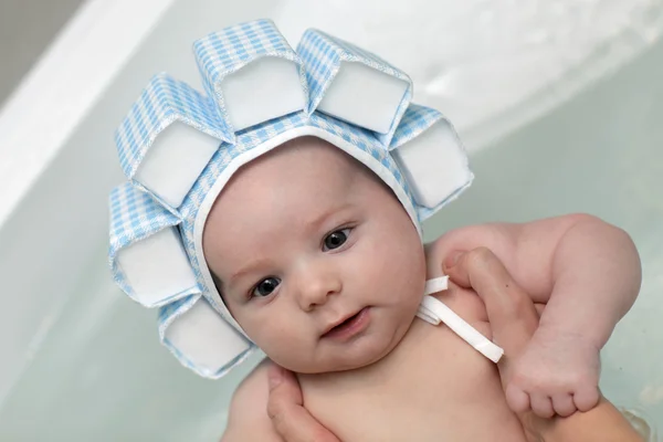 Baby taking bath in swim cap — Stockfoto