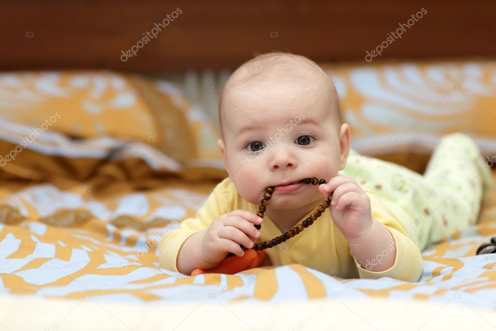 Pensive baby boy sucking beads