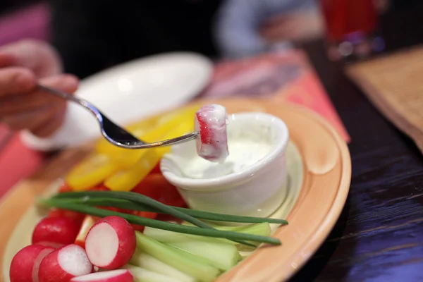 Dipping piece of radish into sauce — Stock Photo, Image