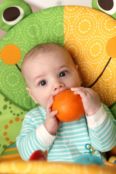 Ребёнок кусает апельсин — стоковое фото